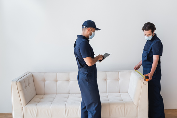 Two people measuring a sofa for reupholstery