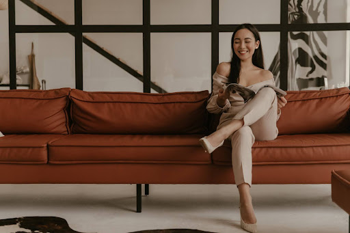 A woman sitting on a beautifully reupholstered brown sofa