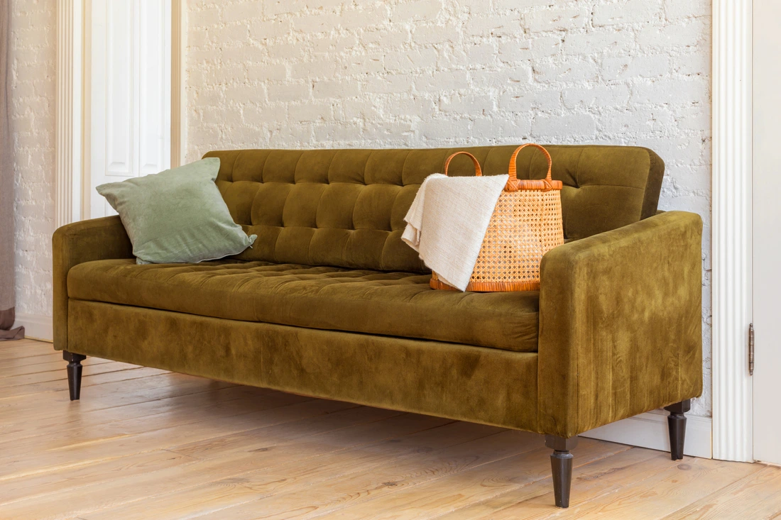 A comfortable brown fabric sofa with throw pillows in a cozy living room, representing budget-friendly upholstery.