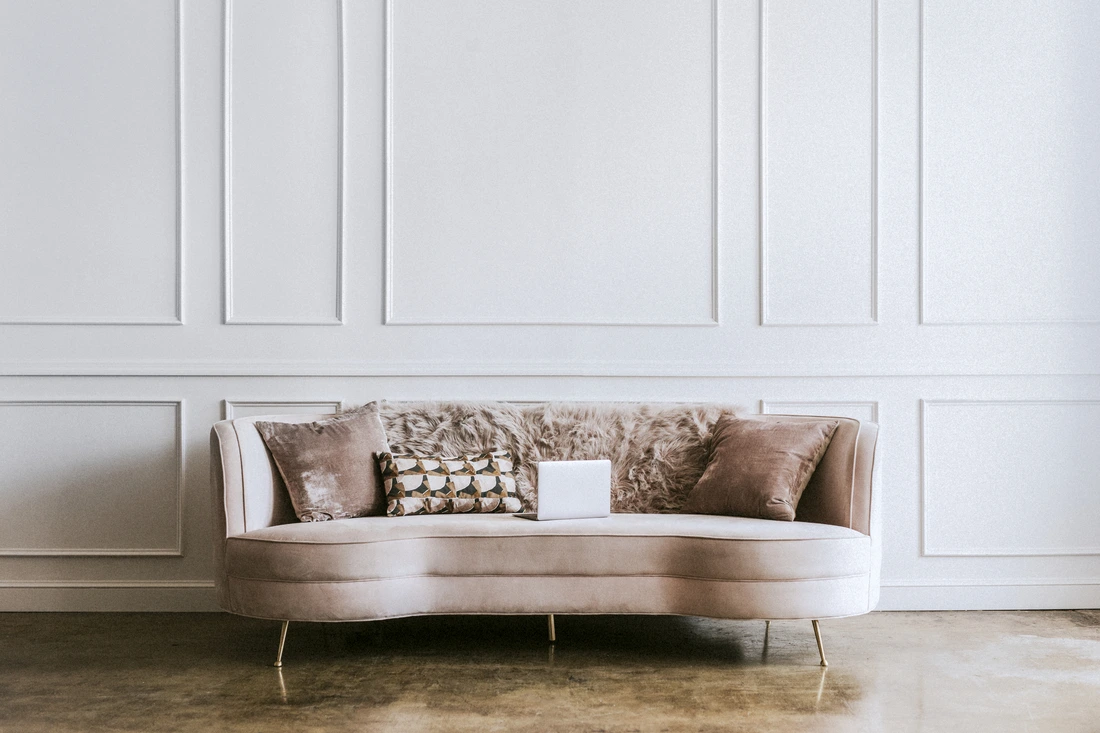 A light pink velvet sofa with decorative pillows in a living room
