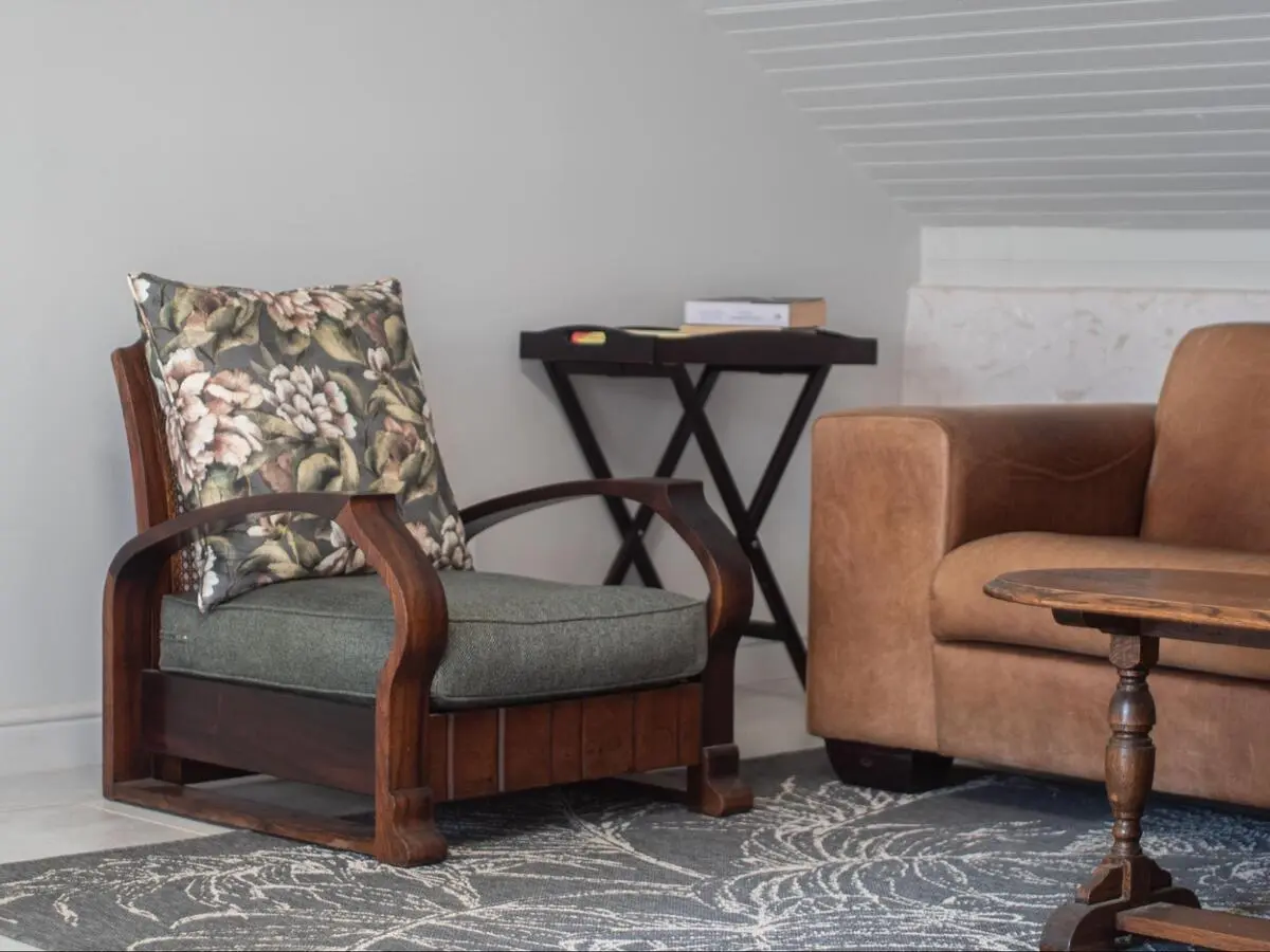 Professionally restored antique wooden armchair with floral cushions in a Singapore home.