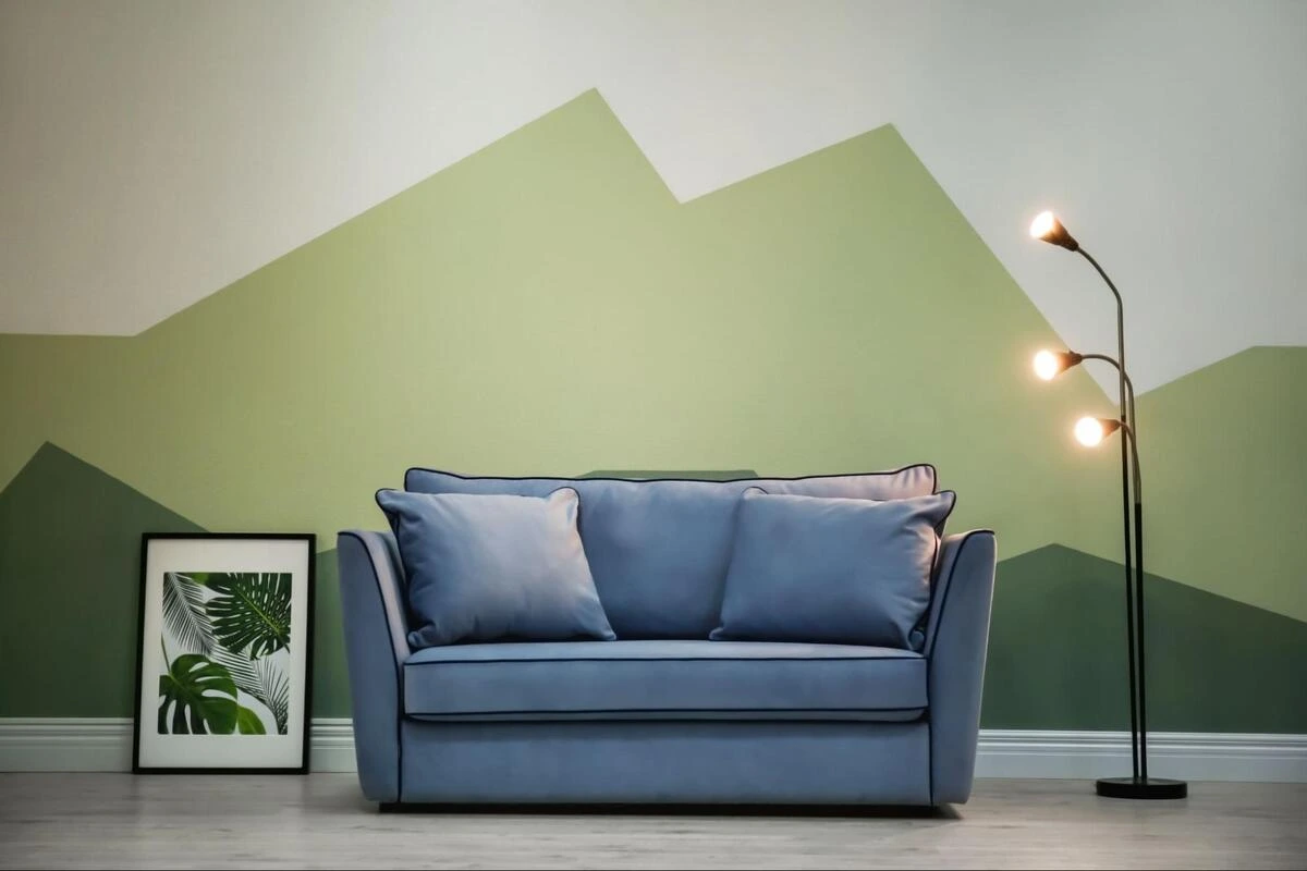 Blue fabric sofa against a geometric painted wall, representing professional sofa reupholstery evaluation