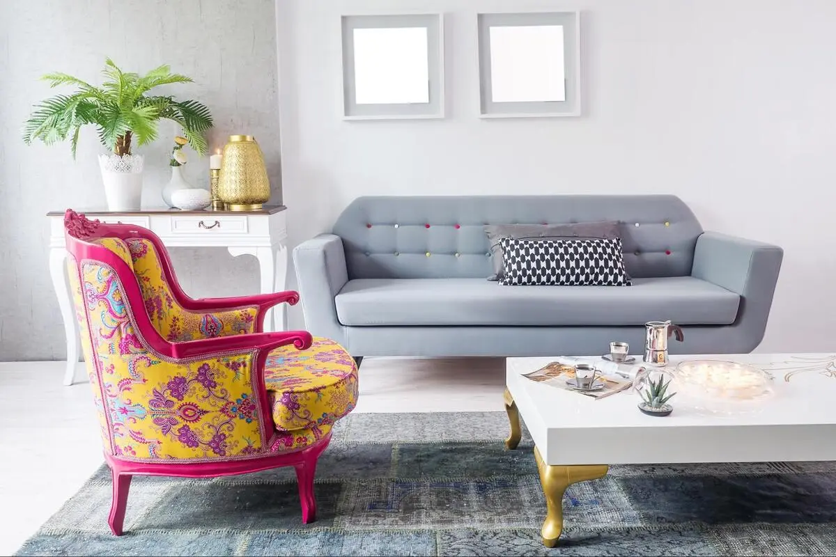 Bright patterned armchair beside a plain grey sofa, illustrating fabric cost differences in sofa reupholstery