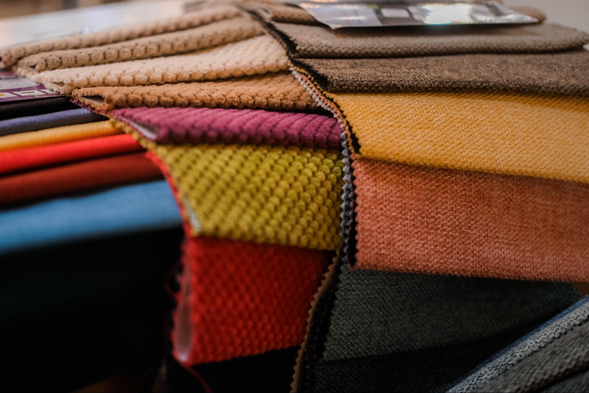Stack of folded upholstery fabric swatches in various colours and textures