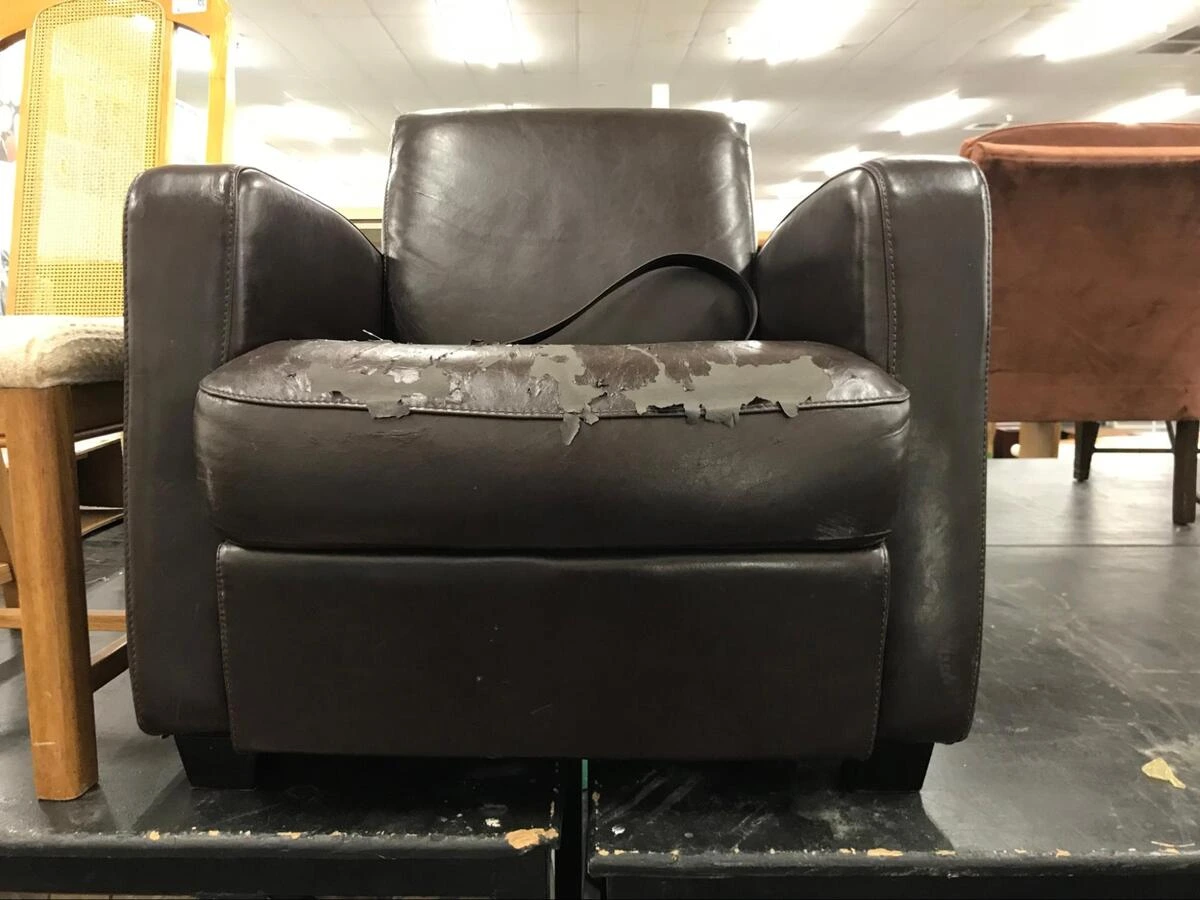 Peeling leather sofa needing repair Dark leather armchair with peeling, flaking seat surface